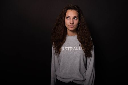 Attractive girl interestedly looking up to side. Isolated on black background