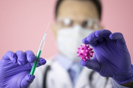 Lab technician with covid-19 virus cell and syringe with vaccine. Stop pandemicの写真素材