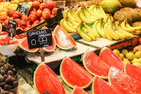 Watermelons strawberries bananas on a Barcelona market counter with price tagの写真素材