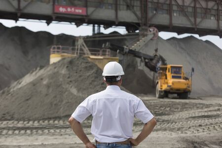 Mining engineer in helmet supervises work of granite workshop
