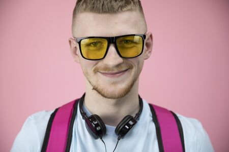 Portait of cute boy in yellow glasses and headphones over neck broadly smiles.の写真素材