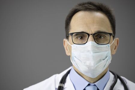 Close up doctor in medical mask looks at camera. Coronovirus outbreak, covid-19の写真素材