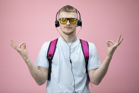 Portrait of relaxed student keeps hands in mudra gesture, closed eyes