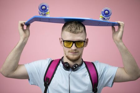 Portrait of student holding pennyboard on head and seriously looking at camera