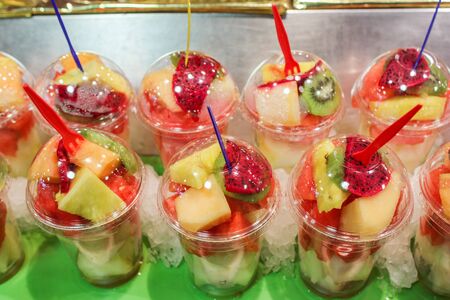 Closeup of assorted chopped fruits melons watermelons strawberries bananas in plastic glasses and plastik fork healthy lifestyle concept fruit dietの写真素材