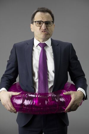 Depressed middle age office worker in panic with lifebuoy, financial problemsの写真素材