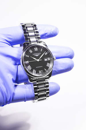 Saint-Imier, Switzerland 31.03.2020 - Closeup image of Longines watch in the male palm in a blue...
