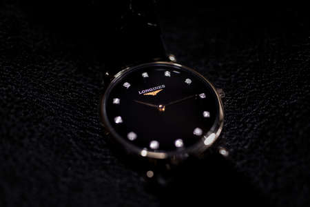 Saint-Imier, Switzerland 31.03.2020 - Closeup image of Longines watch lying on a black leather background stainless steel case black clock face dial decorated with diamonds leather strap selective focus swiss quartz mechanical watch swiss made manufactureのeditorial素材