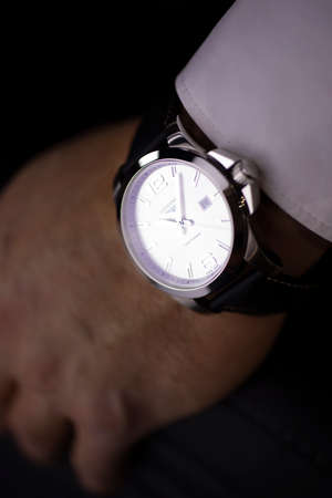 Saint-Imier, Switzerland 31.03.2020 - Closeup fashion image of Longines watch on wrist of man: mans hand in blue jeans pocket with white cuff of plaid shirt. Longines man watch stainless steel case Longines man watch stainless steel case white clock face のeditorial素材