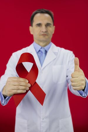 40s medical doctor with big red ribbon for AIDS HIV awareness on red background