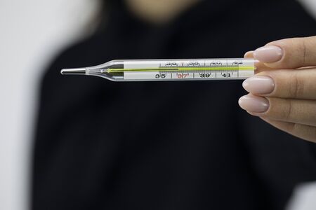 Close up mercury medical glass thermometer in female hand which shows 36,6