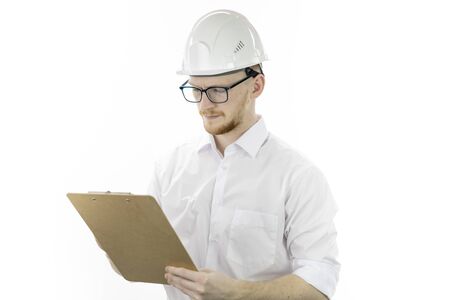 Handsome architector in hard hat makes notes on clipboard on white backgroundの写真素材