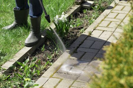 high-pressure washer cleans concrete stones of garden line country house. Spring cleaning concept. Cleaning garden area. natural resources saving concept Dangerous worksの写真素材