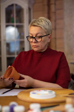 attractive woman coming up with drawing for flowerpot in cozy country house Concentrated woman with...