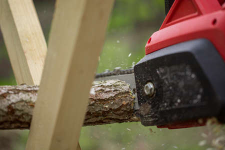 man sawing wood with a chain saw close up. Chainsaw sawn a timber. domestic work concept. Hand...