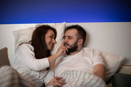 Young beautiful married couple relaxing lying in bed. Attractive caucasian man and woman having fun in bedroom. Love and happiness concept. Romantic mood, love, happy family relaitionship conceptの写真素材