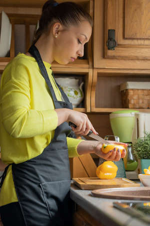 beautiful young girl in black apron cooks in kitchen of cozy wooden country house. Rustic style. healthy eating concept.の写真素材