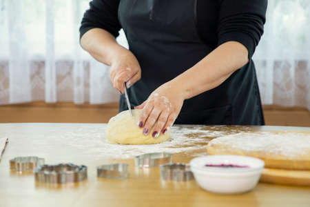 Female baker cooking bread, close up of woman hands mom grandma mother slicing raw dough ball...