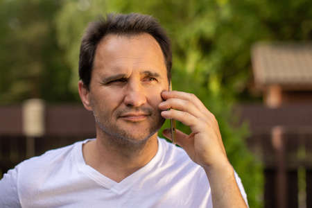Portrait of happy businessman with mobile phone outdoors. Happy man talking by smartphone, call for...