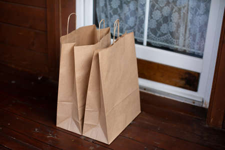 Kraft paper bags at entrance to country house. Contactless delivery of goods and products during...