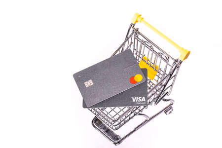 NY, USA - August 25, 2020: Two credit cards Visa and Mastercard platinum on shopping cart isolated on white background. Services of online cashless payment operations, banking security for e-commerceのeditorial素材