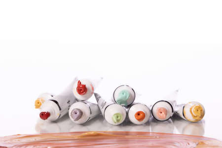 Pile of colorful acrylic paint tubes isolated on white background. Smears of oil paints in...