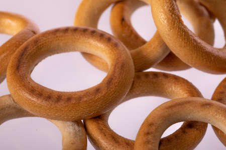 Macro shot of little bagels on light background. Bakery products, dense bread rolls in shape of...