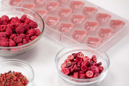 Heart shape confectionery mold with melted ruby chocolate and dried red berries species filling, hand-crafted premium homemade candies for St. Valentines Day, wedding, anniversary. Love symbolの写真素材