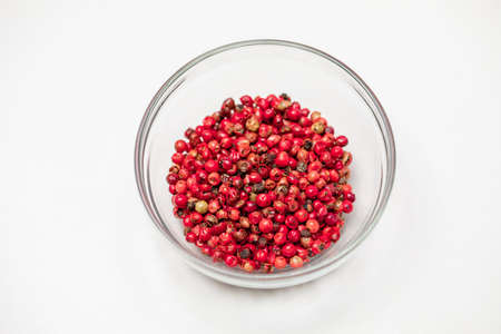 Red peppercorns in glass bowl isolated on white background, organic hot species, dried pepper corns balls, indian natural spice. Food concept, chili pepper grains cosmetic ingredients. Text spaceの写真素材