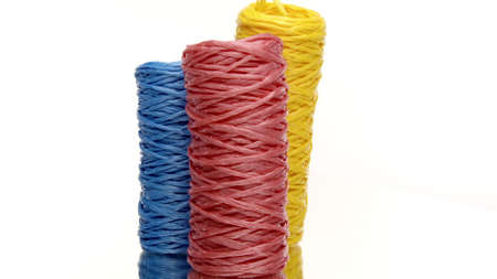 Three skeins of colorful recycled plastic twine rotating on isolated white background. Hank of nylon rope knot strings in motion. Eco-friendly materials, ecology concept. Copy spaceの写真素材