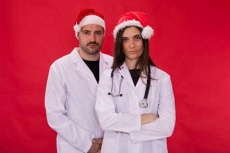 Two tired doctors male and female in Santa Claus hats looking at camera. professional fatigue...