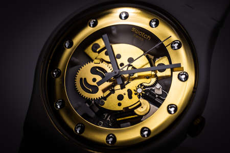 London, GB 07.10.2020 - Swatch swiss made quartz watch on black backdrop. plastic case open clock...
