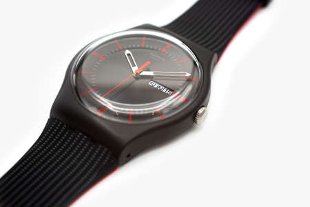 Geneve, Switzerland 07.10.2020 - Swatch cheapest trendy swiss made plastic watch close up, simple black design, Red seconds arrow, Sunday 15 on calender. Value Price concept.のeditorial素材