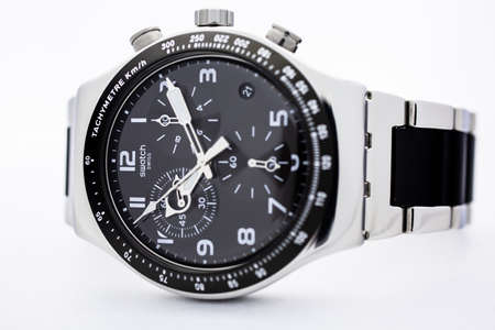 London, GB 07.10.2020 - Swatch classic design swiss made mechanical mens watch isolated on white background. metal case tachymeter, date 21, black dialのeditorial素材
