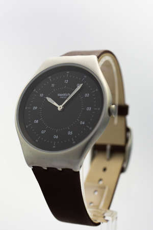 London, GB 07.10.2020 - Swatch on black wristwatch dial of swiss made quartz watch. metal case, stylish mens accessory. Swatch Group watch production. 10.06 pmのeditorial素材