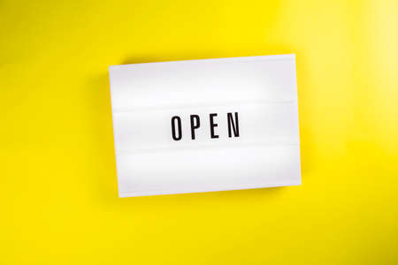 Open word on lightbox on yellow background isolated. Top view, flat lay. quarantine opening, isolation end concept Open restaurant, cafe, exhibition, office center conceptの写真素材