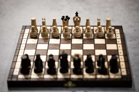 Wooden Chess pieces on board, arranged in incorrect initial position selective focus backlit. White king is at wrong Chessboard square. Royal mistake, transfer of powers, secret court intriguesの写真素材