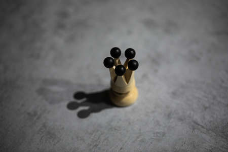white queen chess piece casts shadow on gray table. single wooden figurine, lonely queen without entourage. minimalist design, concept of solitudeの写真素材