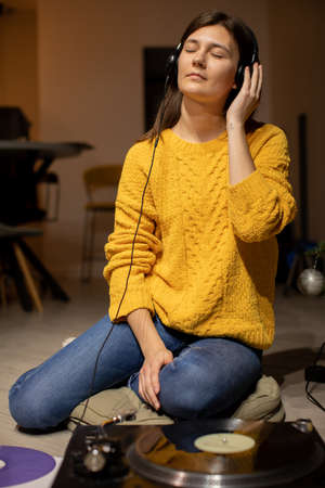 girl sitting on floor enjoys to music with headphones and analog turntableの写真素材