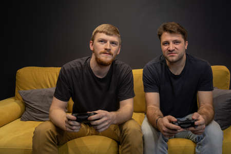 two cheerful handsome guys play passionately video game holding console gamepadの写真素材