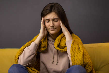 brunette girl grabbed head in hands suffering from headache with pain expressionの写真素材