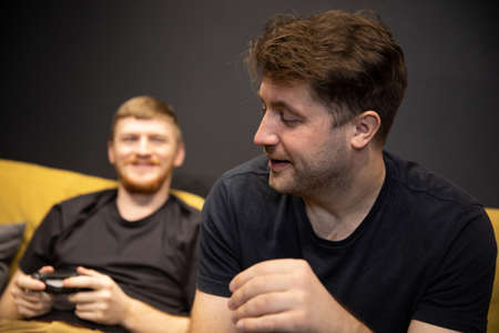 gamer upset at losing videogame. Smiling opponent comforts loser selective focusの写真素材