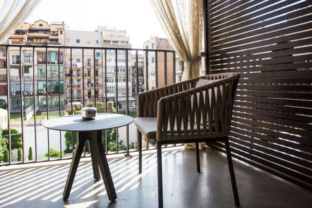 designer chair, table and ashtray on hotel balcony overlooking courtyard with everyday city life. Travel concept. Lost in quarantine, missing on excursion concept. Private area single roomの写真素材