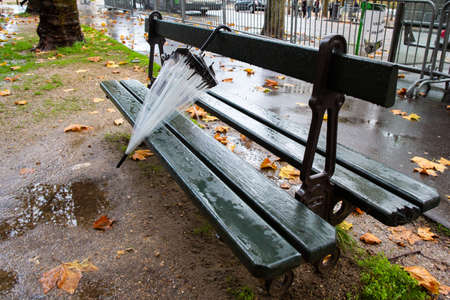Paris, France, 1.11.2019 - transparent umbrella forgotten on green street bench in Champs Elysees on...