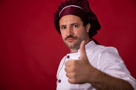 Portrait of handsome chef in uniform showing like sign, best cooking tipsの写真素材