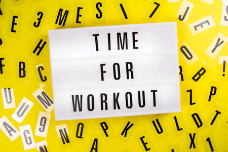 Lightbox with text TIME FOR WORKOUT on yellow background with black letters randomly scattered. Concept of everyday training, keep-fit, physical exercise session, health care, active lifestyleの写真素材