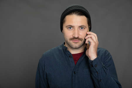 Stylish man in casual wear talking on mobile phone, grey background, copy spaceの写真素材