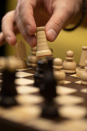 Hand taking next step on chess game. Human hand moving wooden white rook pieceの写真素材