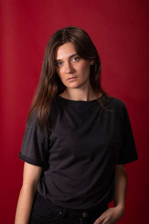 Portrait of young lesbian woman in casual wear with no makeup on red backgroundの写真素材