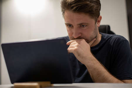Close up portrait of Focused unshaven handsome guy looking tabletの写真素材